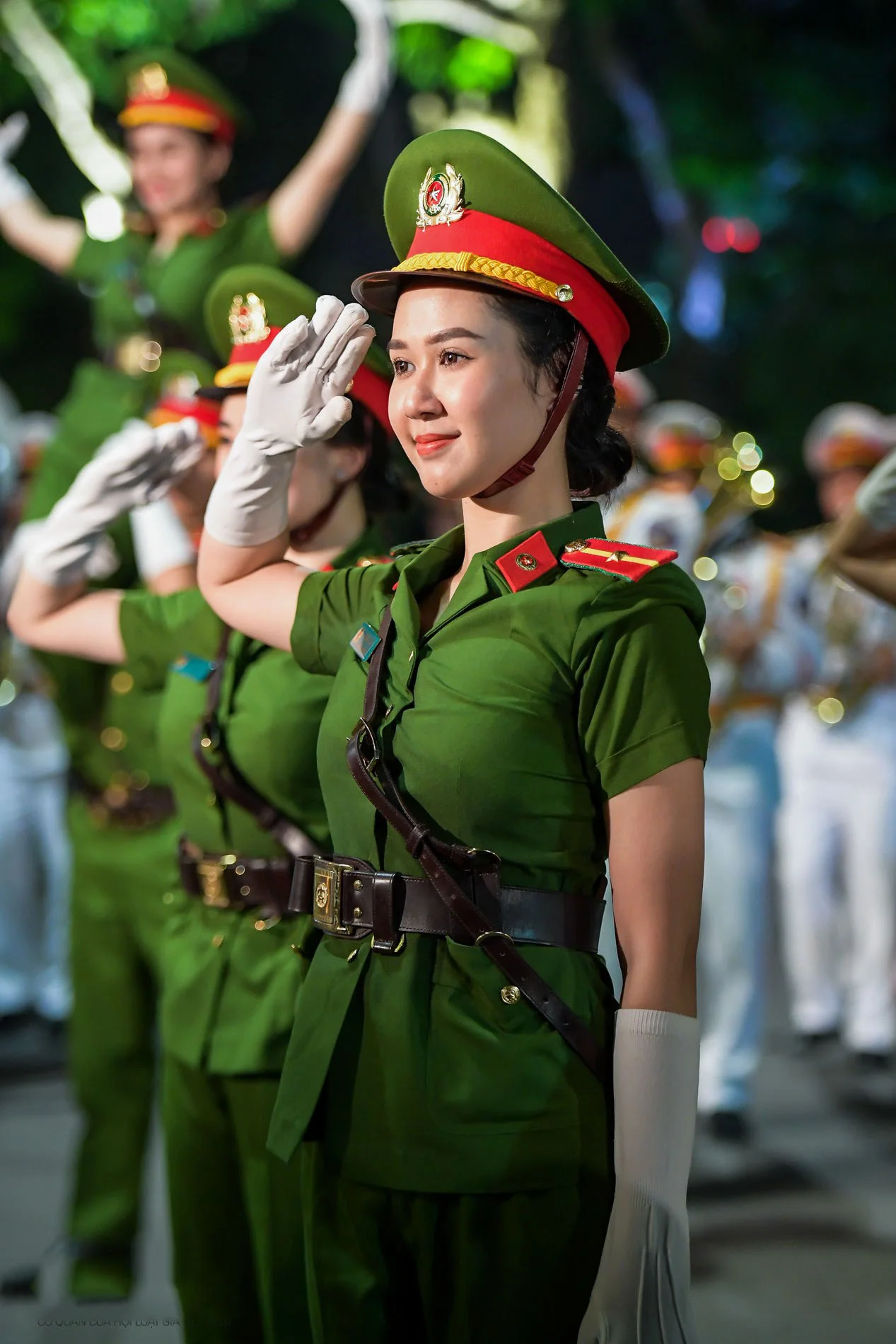 Nữ công an mặc đồng phục xanh thực hiện động tác chào trong đội hình
