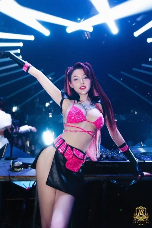 Nữ DJ ngân 98 sex biểu diễn trên sân khâu với ánh sáng xanh và thiết bị âm thanh chuyên nghiệp.