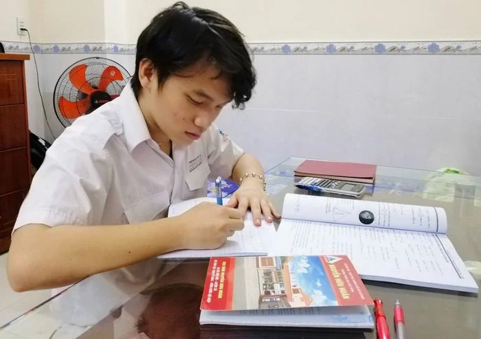 Hình ảnh học tập của nam sinh với sách vở và tài liệu tại bàn học.