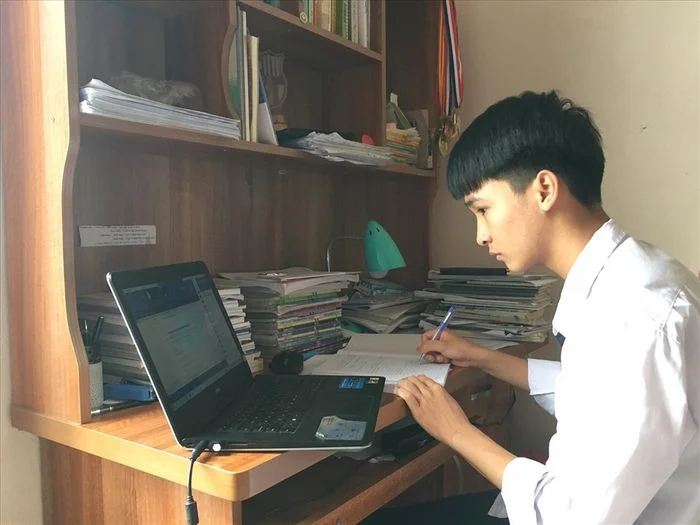 Nam sinh học tập với máy tính và tài liệu trên bàn