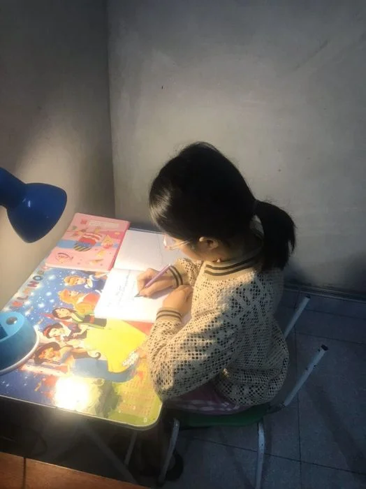 Hình ảnh học tập của một bé gái dưới ánh đèn bàn vào buổi tối