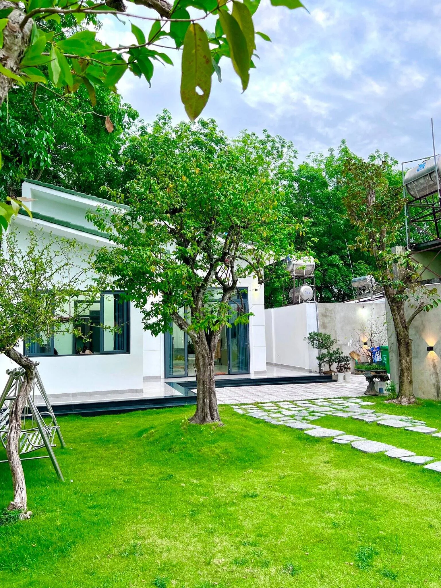 Mẫu nhà cấp 4 đẹp có thiết kế hiện đại với sân vườn xanh mát và lối đi lát đá